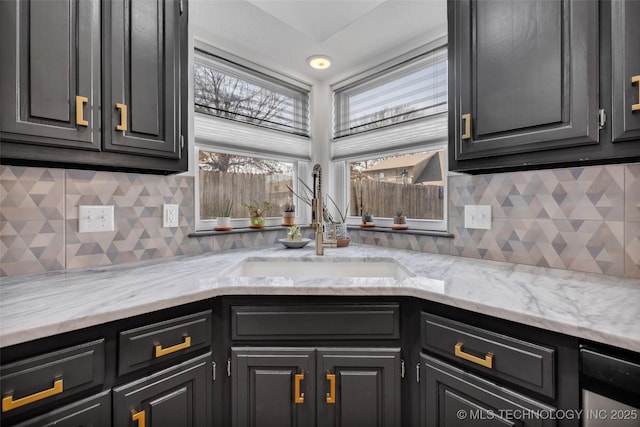 kitchen featuring light stone countertops, sink, and backsplash