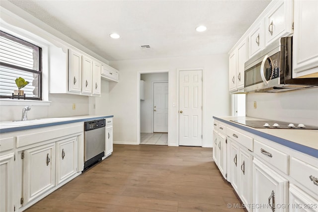 kitchen featuring stainless steel appliances, white cabinetry, sink, and hardwood / wood-style floors