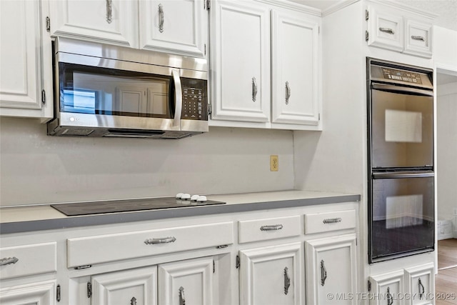 kitchen featuring wood-type flooring, white cabinets, and black appliances