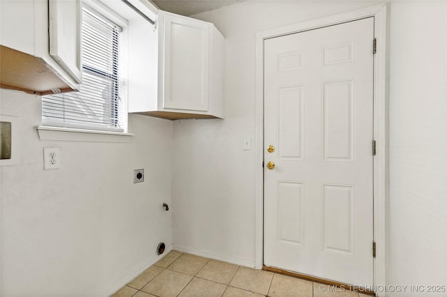 washroom featuring electric dryer hookup, light tile patterned floors, and cabinets