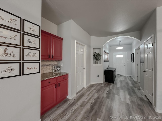 kitchen featuring dark stone countertops, decorative backsplash, and light hardwood / wood-style flooring