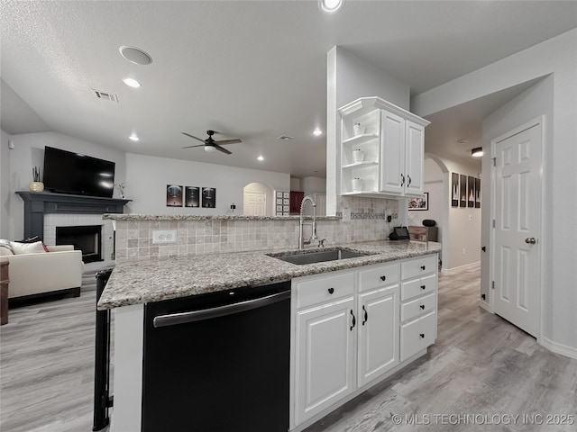 kitchen featuring light stone counters, black dishwasher, sink, and white cabinets