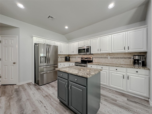 kitchen with appliances with stainless steel finishes, white cabinetry, gray cabinetry, a kitchen island, and vaulted ceiling