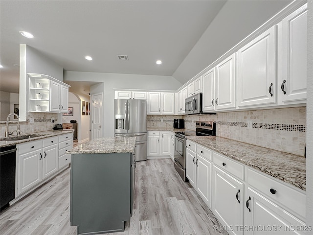 kitchen with sink, white cabinets, a center island, light stone counters, and stainless steel appliances