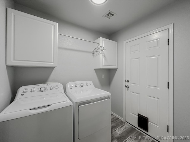 washroom featuring dark hardwood / wood-style flooring, washing machine and dryer, and cabinets