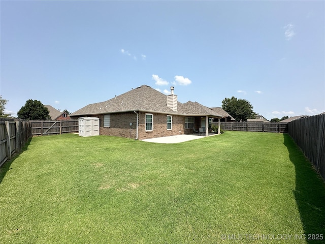 rear view of property featuring a storage shed, a lawn, and a patio area