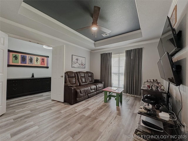 living room with hardwood / wood-style flooring, ceiling fan, a tray ceiling, and crown molding