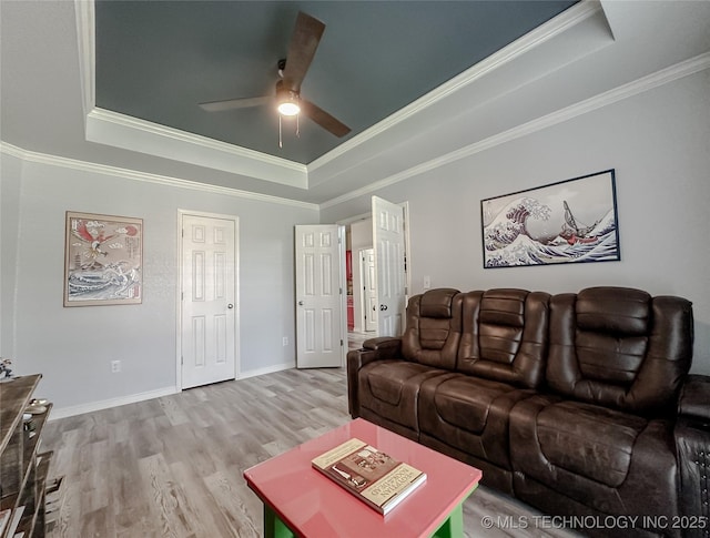 living room featuring hardwood / wood-style flooring, ornamental molding, and a raised ceiling