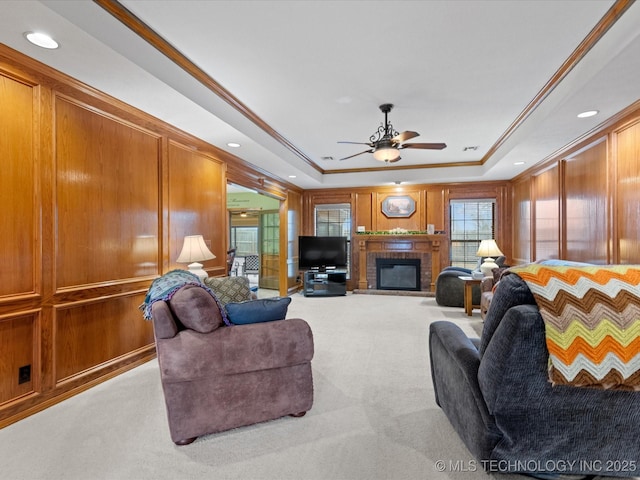 living room featuring ornamental molding, a fireplace, a raised ceiling, and light carpet