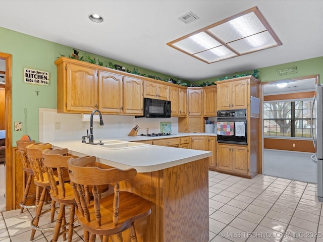 kitchen featuring a kitchen bar, kitchen peninsula, sink, and black appliances