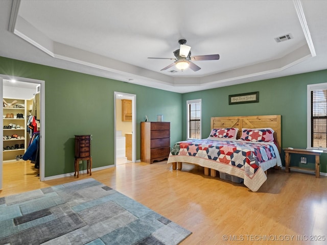 bedroom featuring a raised ceiling, hardwood / wood-style floors, and multiple windows