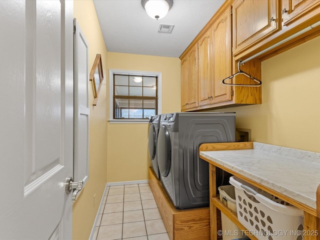 laundry area with cabinets, washing machine and dryer, and light tile patterned floors