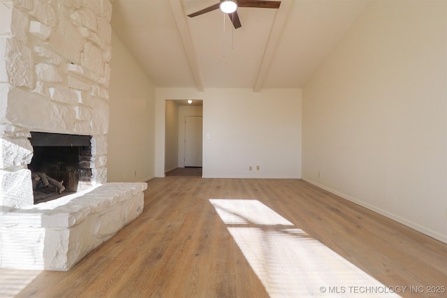 unfurnished living room featuring ceiling fan, a stone fireplace, vaulted ceiling with beams, and light hardwood / wood-style floors