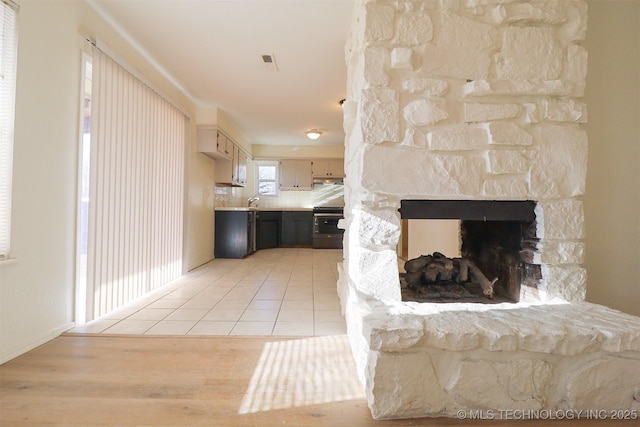 tiled living room with a stone fireplace