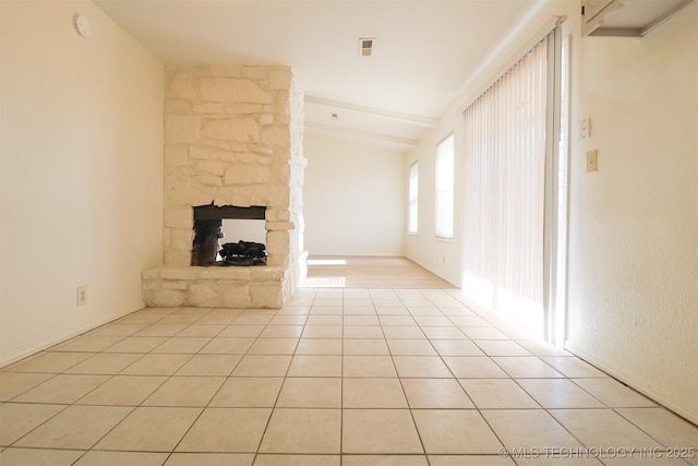 unfurnished living room featuring a fireplace, lofted ceiling with beams, and light tile patterned flooring