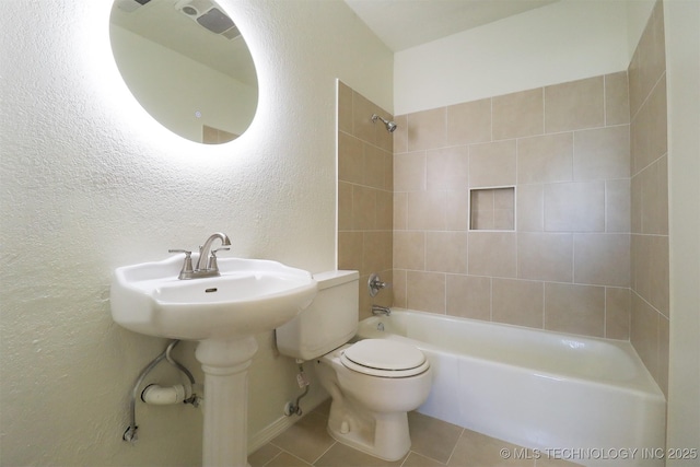 bathroom with tile patterned floors, toilet, and tiled shower / bath combo