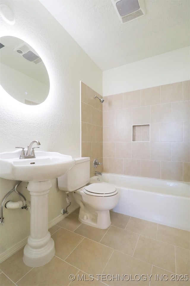 bathroom featuring tile patterned flooring, toilet, and tiled shower / bath