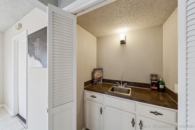 bar featuring sink, white cabinets, and a textured ceiling