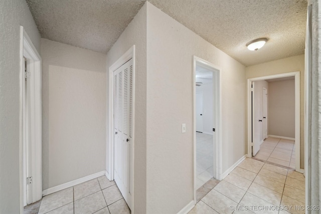 corridor featuring light tile patterned floors and a textured ceiling