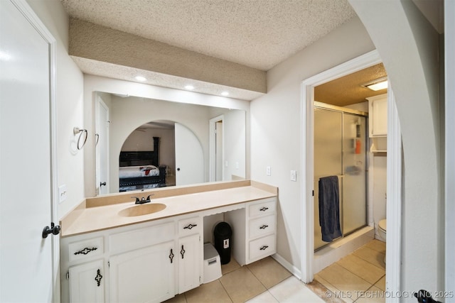 bathroom with tile patterned floors, toilet, a textured ceiling, vanity, and a shower with door