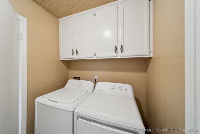 laundry room featuring cabinets, washing machine and clothes dryer, and a textured ceiling