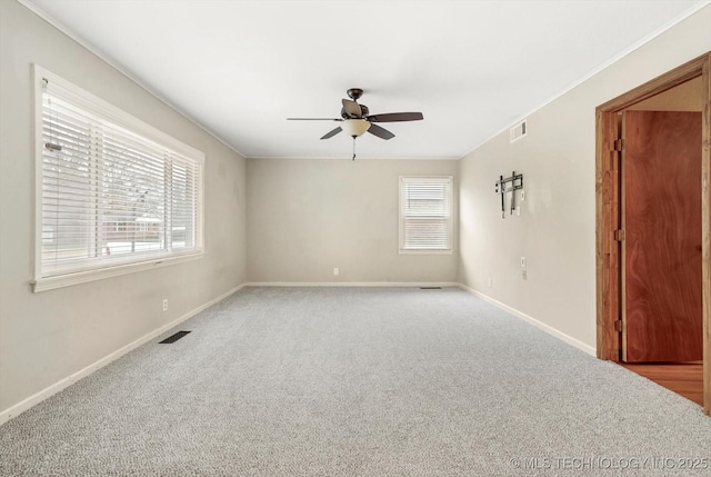 unfurnished room featuring ceiling fan, ornamental molding, plenty of natural light, and carpet