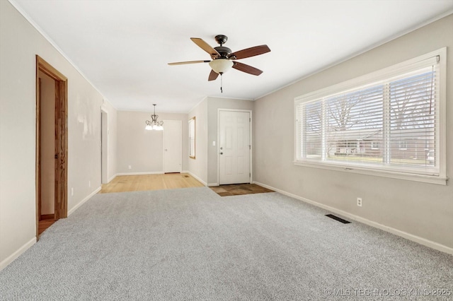 carpeted empty room featuring crown molding and ceiling fan with notable chandelier