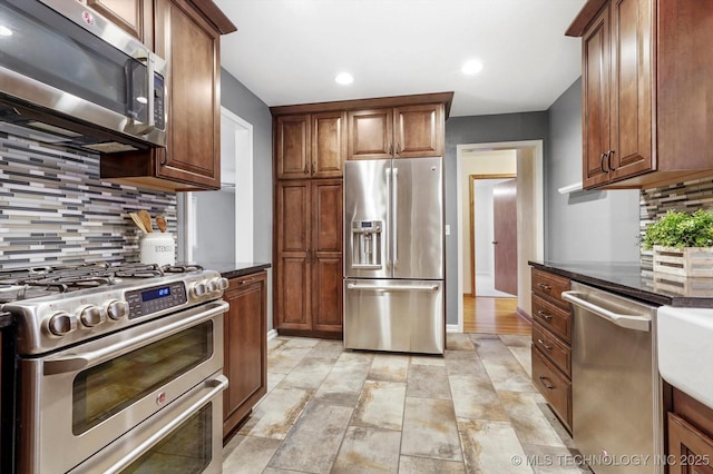 kitchen with dark stone countertops, backsplash, and appliances with stainless steel finishes