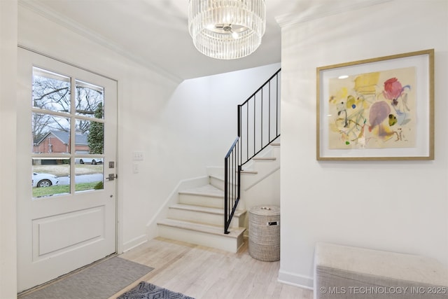 entrance foyer featuring a notable chandelier, ornamental molding, and light wood-type flooring