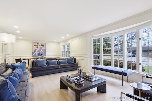 living room with ornamental molding, a wealth of natural light, and light wood-type flooring