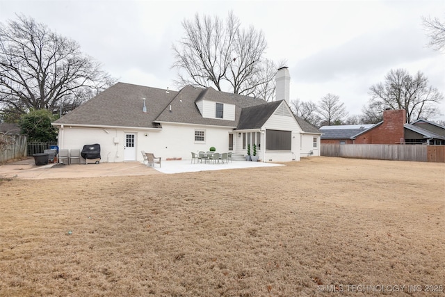 back of property with a yard and a patio