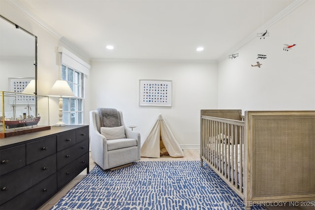 bedroom featuring hardwood / wood-style flooring, ornamental molding, and a nursery area