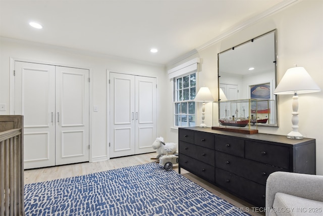 bedroom featuring multiple closets, ornamental molding, and light hardwood / wood-style flooring