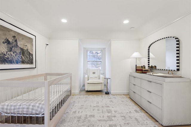 bedroom with crown molding and a nursery area