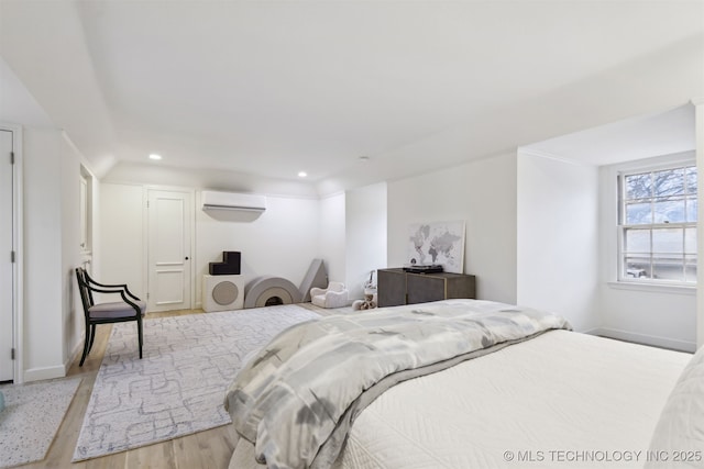 bedroom featuring light hardwood / wood-style floors and a wall unit AC