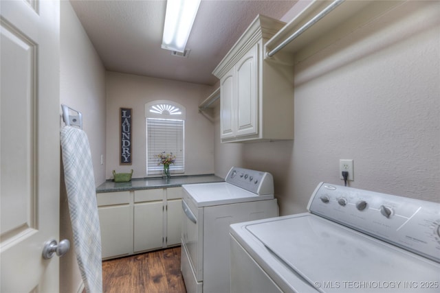 clothes washing area featuring dark wood-type flooring, cabinets, and washing machine and clothes dryer