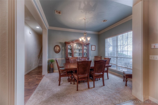 dining area featuring crown molding, wood-type flooring, and a chandelier