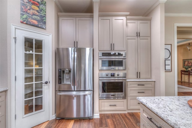 kitchen featuring crown molding, appliances with stainless steel finishes, dark hardwood / wood-style floors, gray cabinets, and light stone countertops