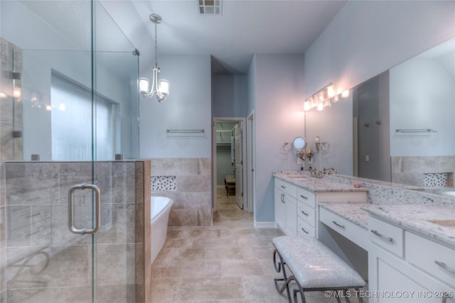 bathroom with vanity, a chandelier, shower with separate bathtub, and tile walls