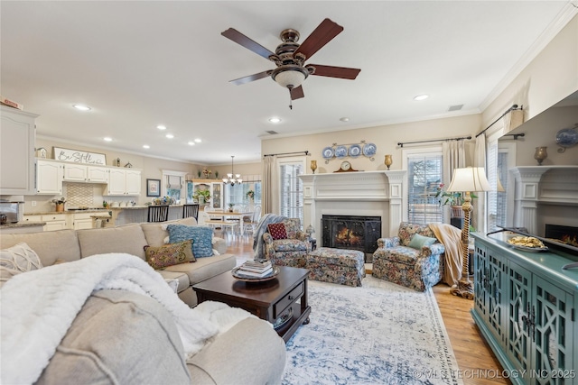 living room with crown molding, ceiling fan, a healthy amount of sunlight, and light hardwood / wood-style floors