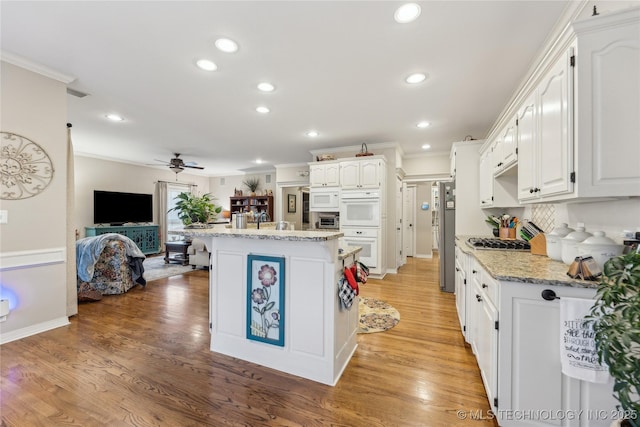 kitchen featuring light stone counters, ornamental molding, stainless steel appliances, and white cabinets