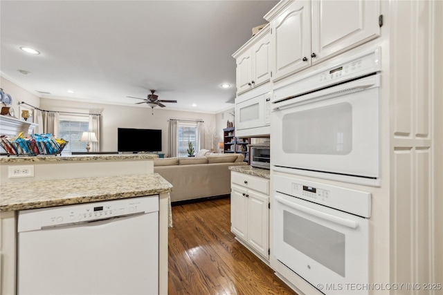 kitchen with light stone counters, white appliances, dark wood-type flooring, and white cabinets