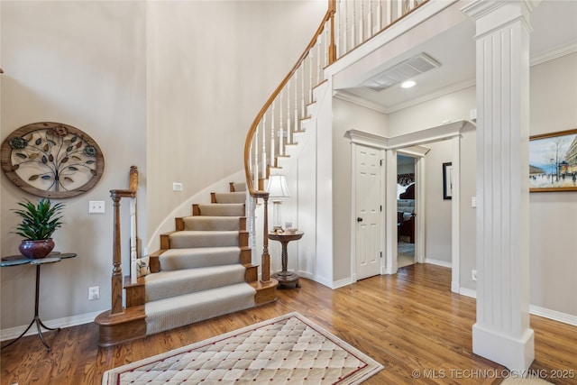 foyer featuring hardwood / wood-style floors, crown molding, and decorative columns