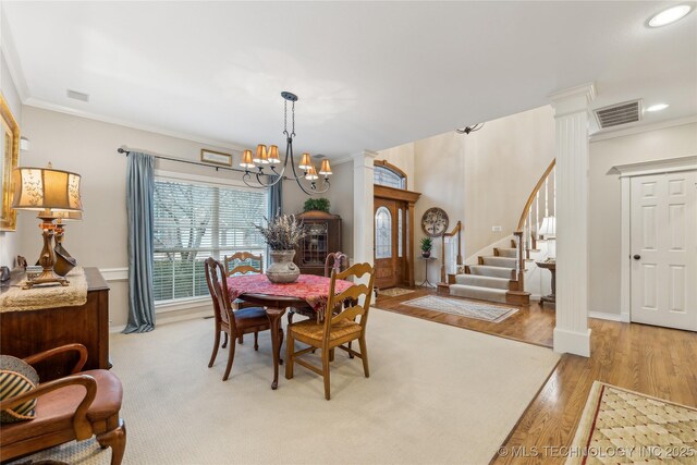 dining space with crown molding, light hardwood / wood-style floors, decorative columns, and a notable chandelier