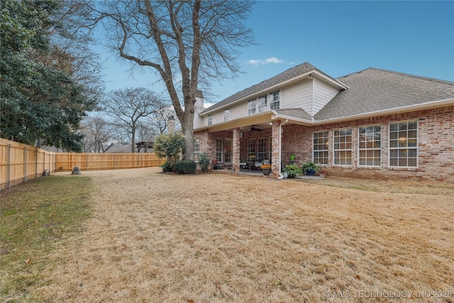 rear view of house featuring ceiling fan and a yard