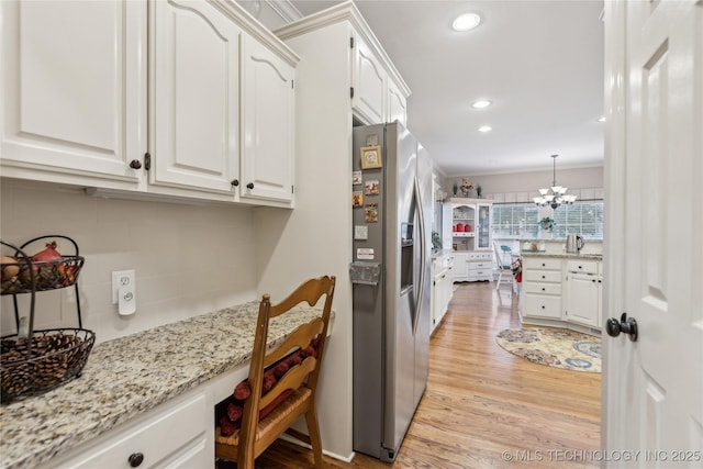 kitchen with pendant lighting, white cabinets, light stone counters, stainless steel fridge with ice dispenser, and light wood-type flooring