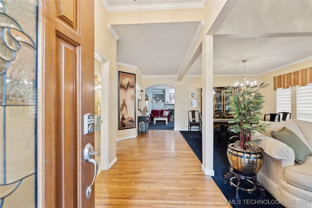 entryway with crown molding, light hardwood / wood-style floors, and a notable chandelier