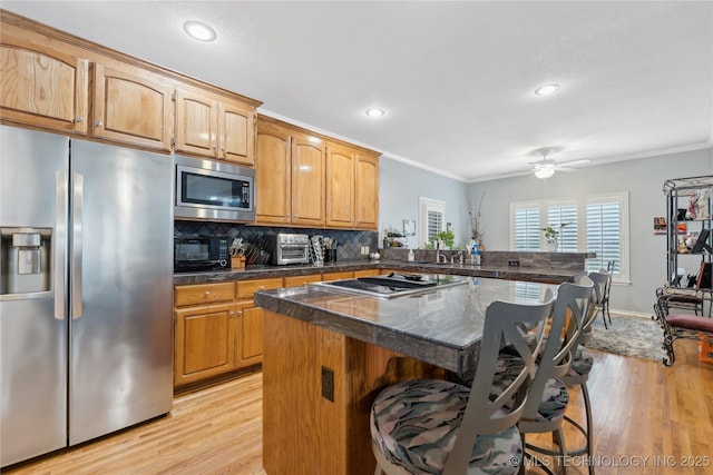 kitchen featuring stainless steel appliances, crown molding, a kitchen island, and a breakfast bar