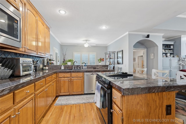 kitchen with ornamental molding, appliances with stainless steel finishes, light hardwood / wood-style floors, and sink