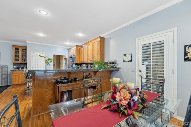 dining room with ornamental molding and light hardwood / wood-style floors